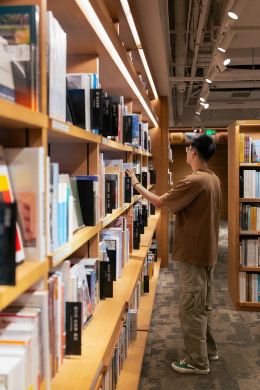 a man is picking up some books from a shelf