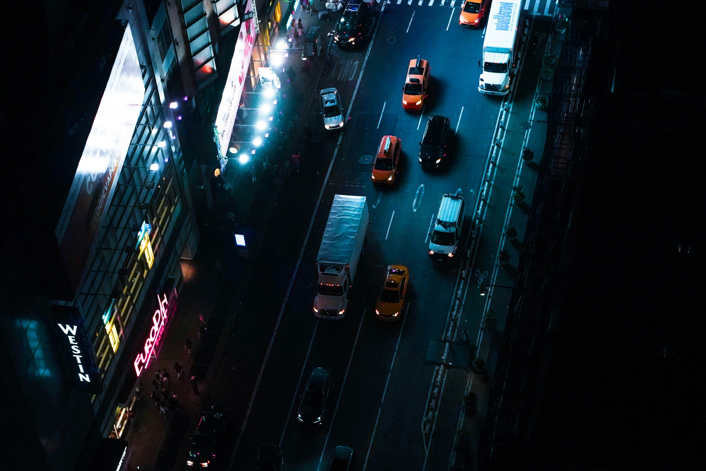 a couple of cars are traveling down the road at night