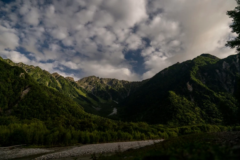 there is a green valley with a creek in the foreground