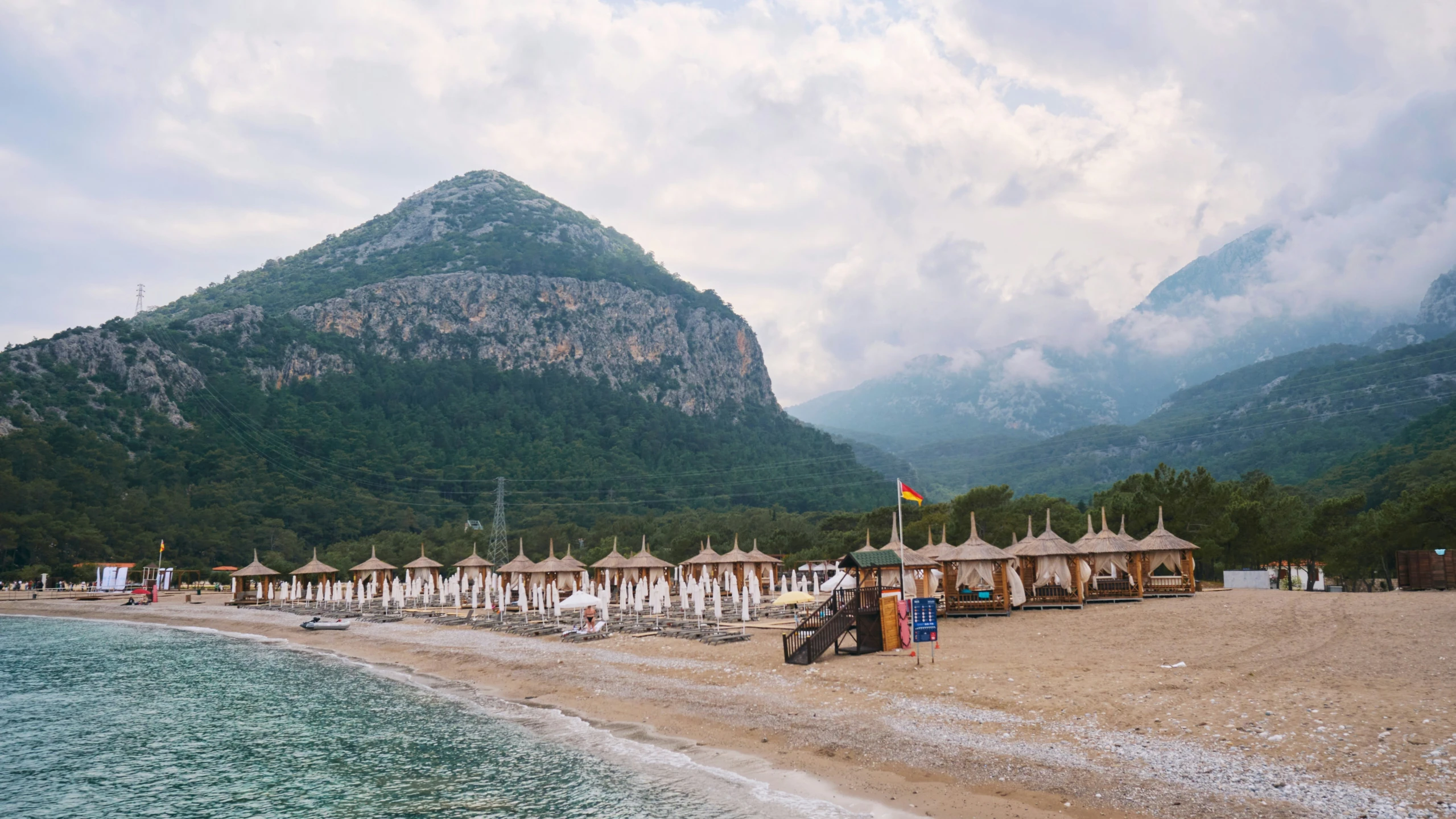 umbrellas and chairs line a sandy beach on an overcast day