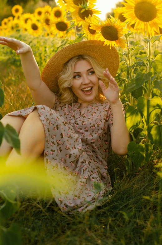 a woman wearing a hat sitting in the grass