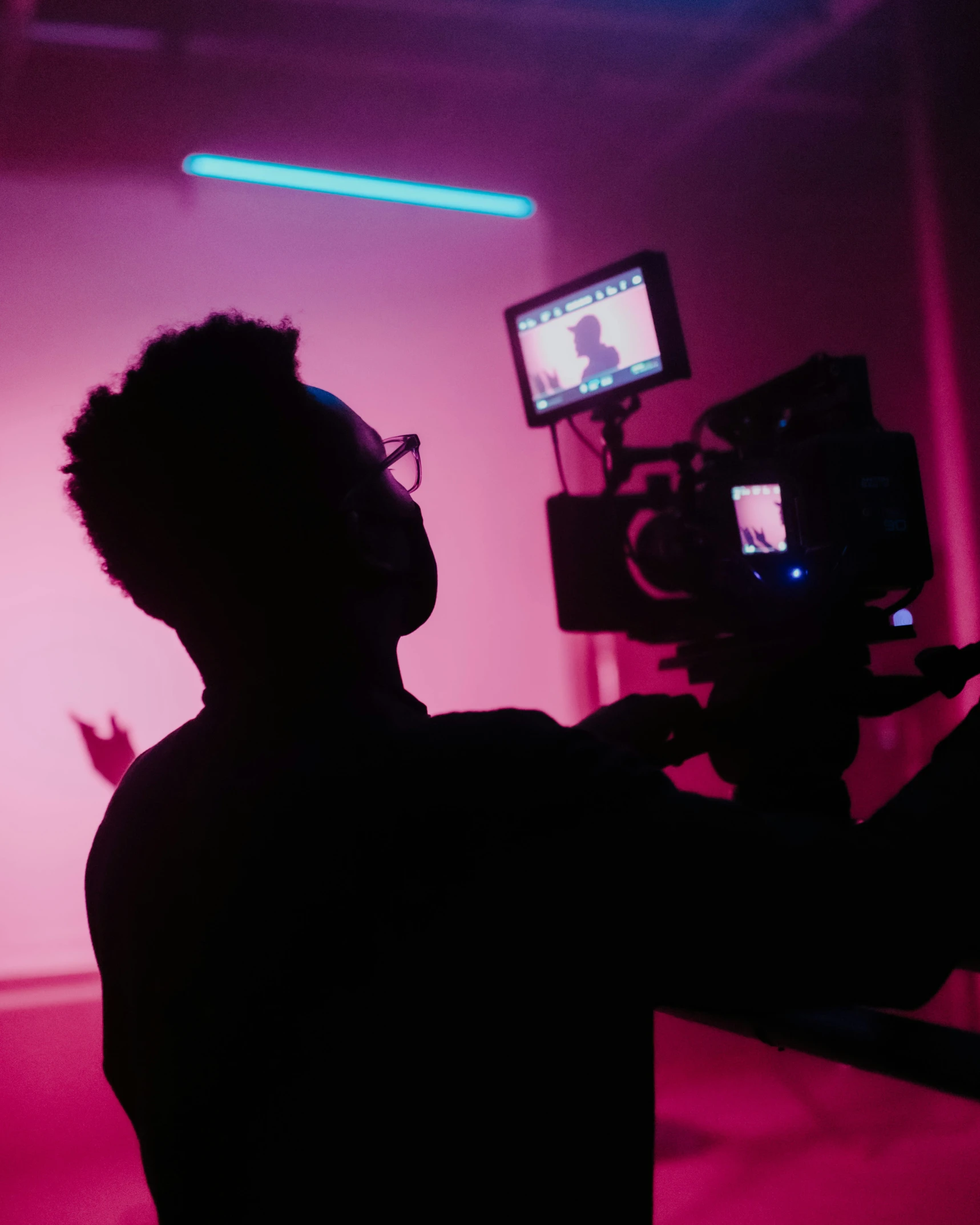 a person taking a picture with a video camera in a pink room