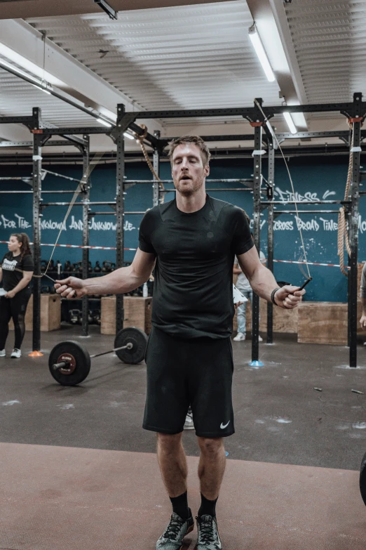 a man holding his arms out with other men in the background doing cross - fit