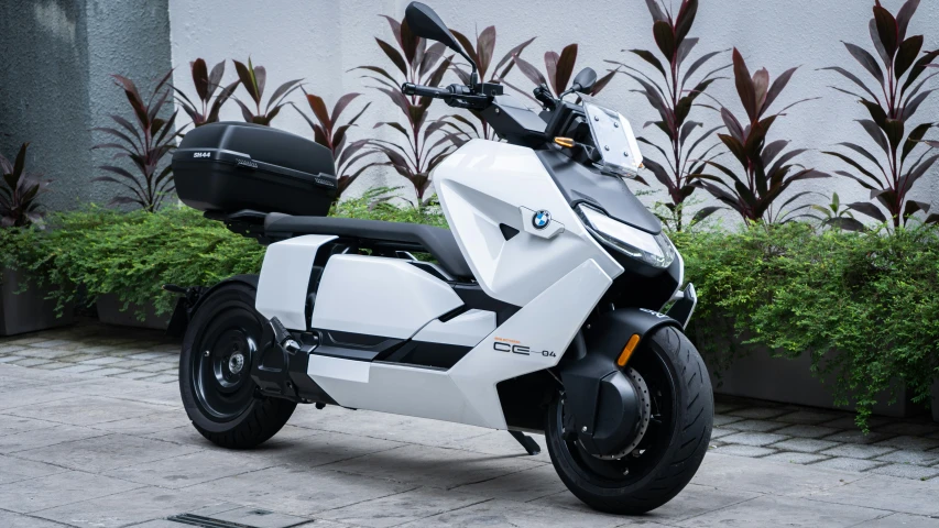 a white bmw motorcycle parked in front of a plant