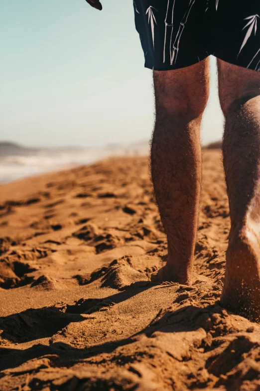 a person in black shorts standing in the sand