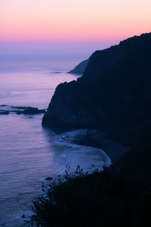 an ocean at sunset near a mountain