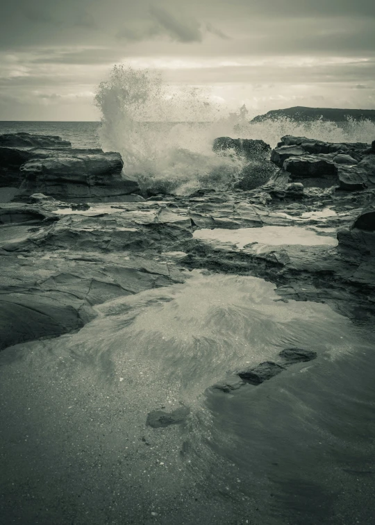 a person walking along the water towards waves crashing onto the shore