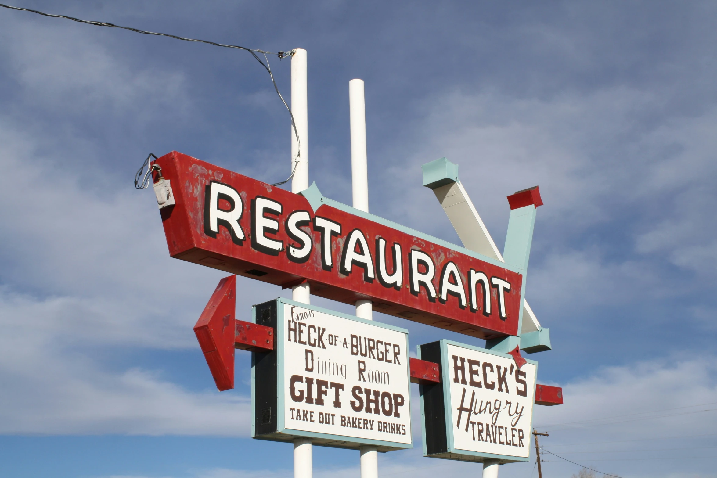 a restaurant sign stands in front of some blue skies