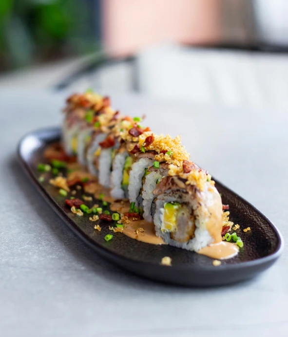 a sushi with lots of toppings sitting on a table