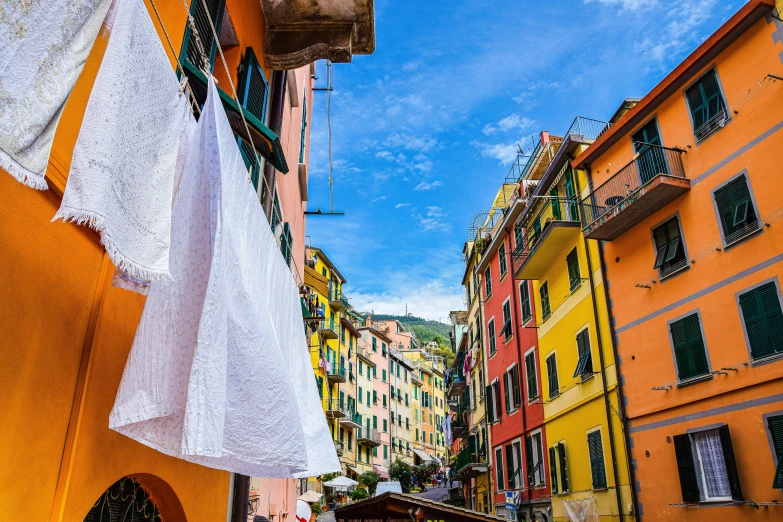 a narrow alley with many colors and white sheets hanging from the clothesline