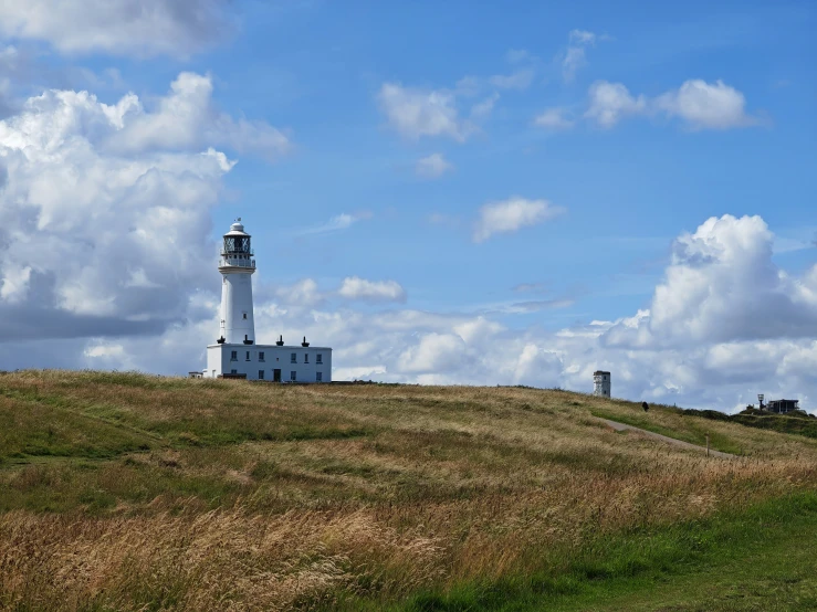 white light house sits on top of a hill