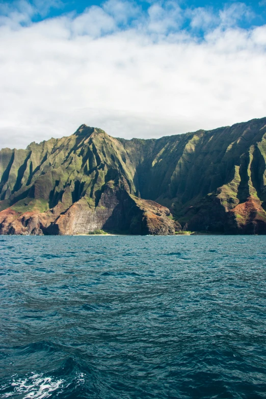 a sail boat in the water with mountains in the distance