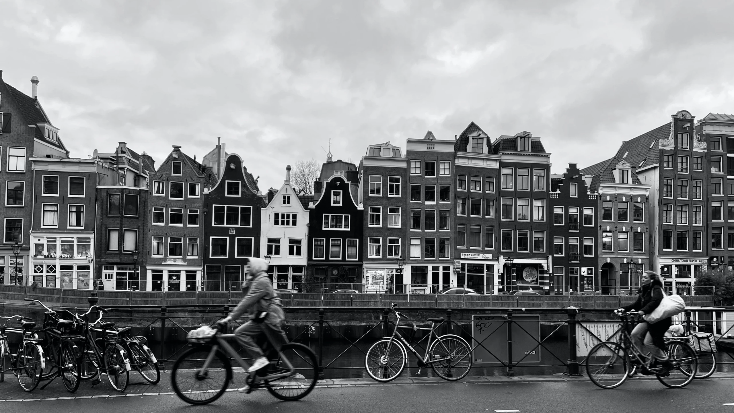 black and white pograph of people on bikes passing by