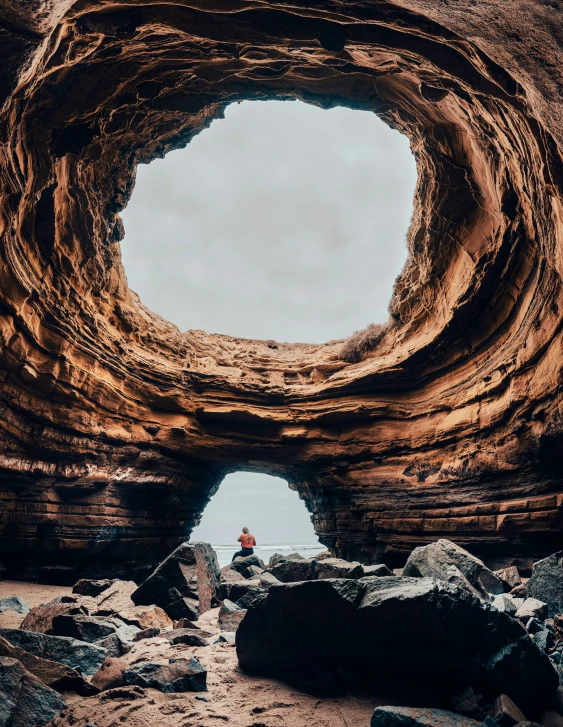 man standing at the entrance of an old rock formation