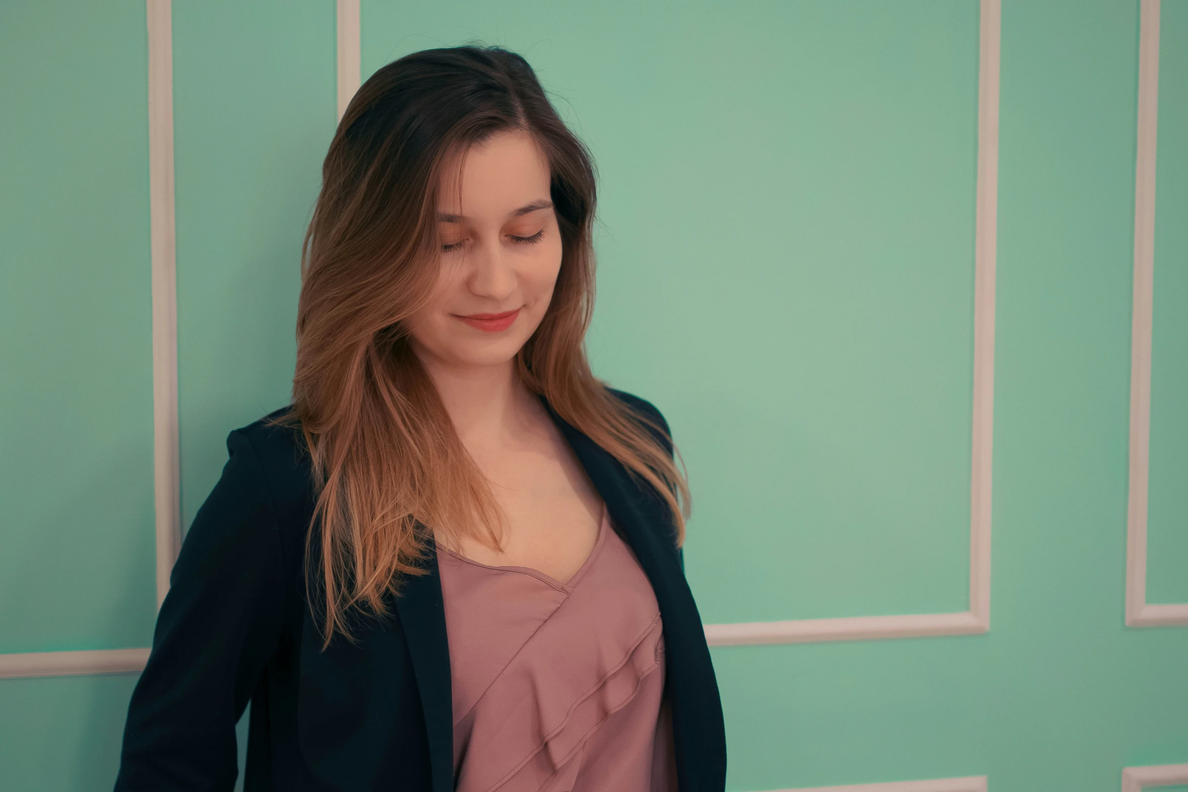 woman in business coat leaning against the wall