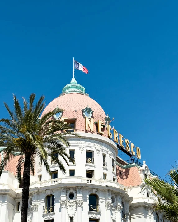 large dome of building that says grand el in front of palm trees