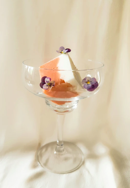 an individual dessert in a glass dish with flowers