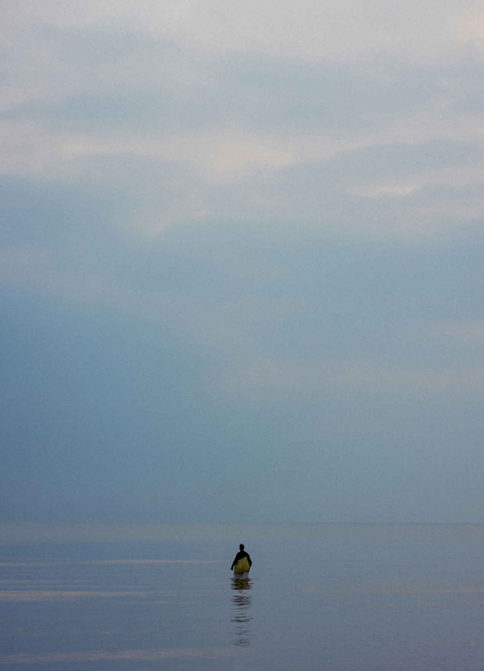 a lone kayaker on the water surrounded by some clouds