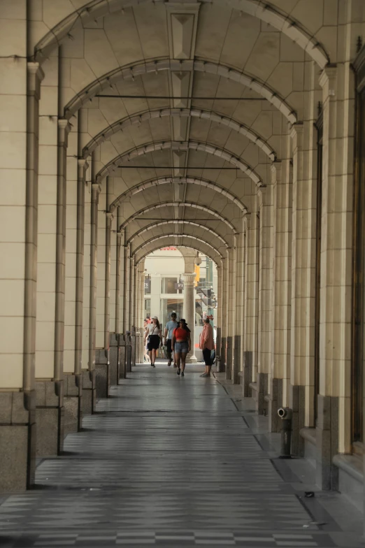 a street with pillars and people walking underneath