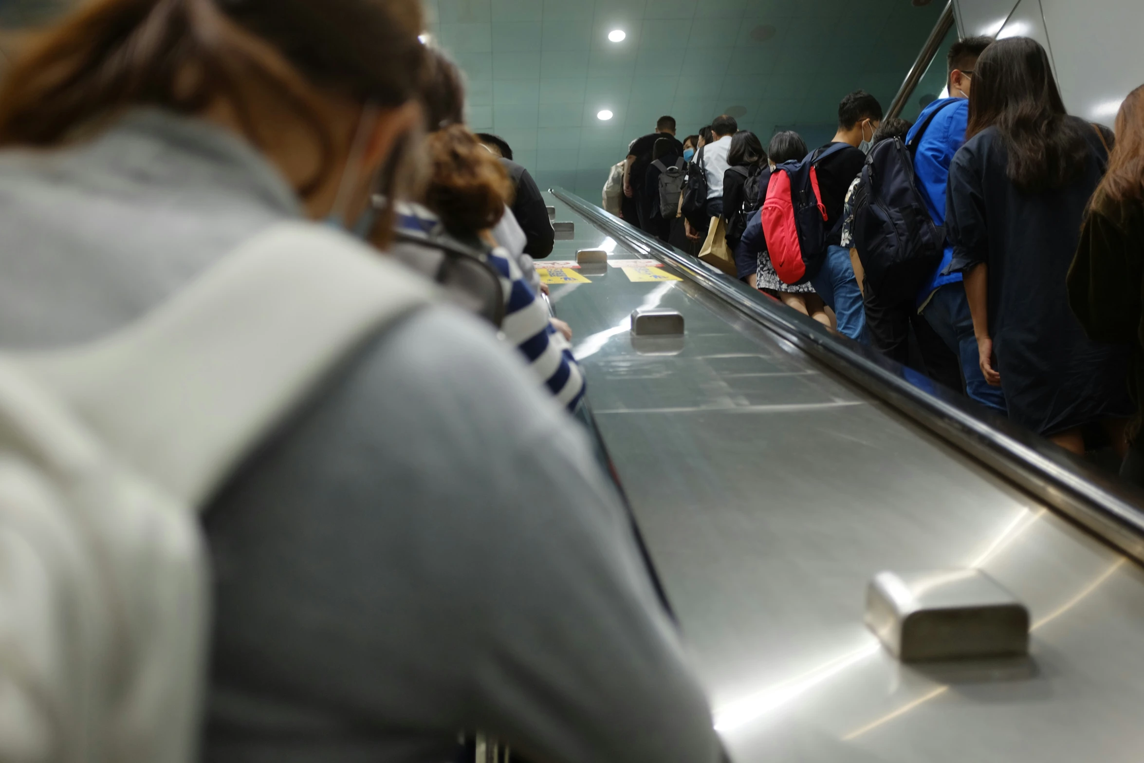 a group of people with baggage are riding on an escalator