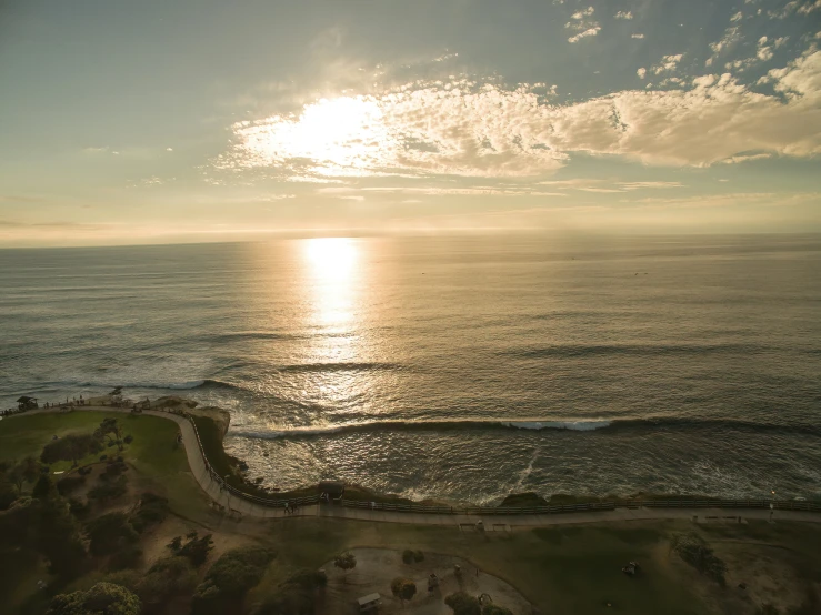 a bird - eye view shows the sun setting over a ocean, and two houses on the land