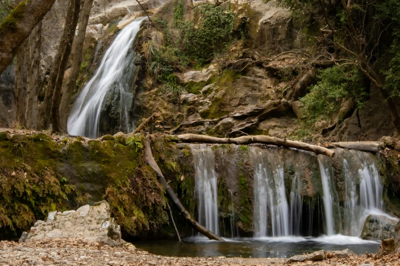 small waterfall flowing down a green forested hill