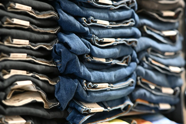 pile of blue jeans in rows, with one folded on top