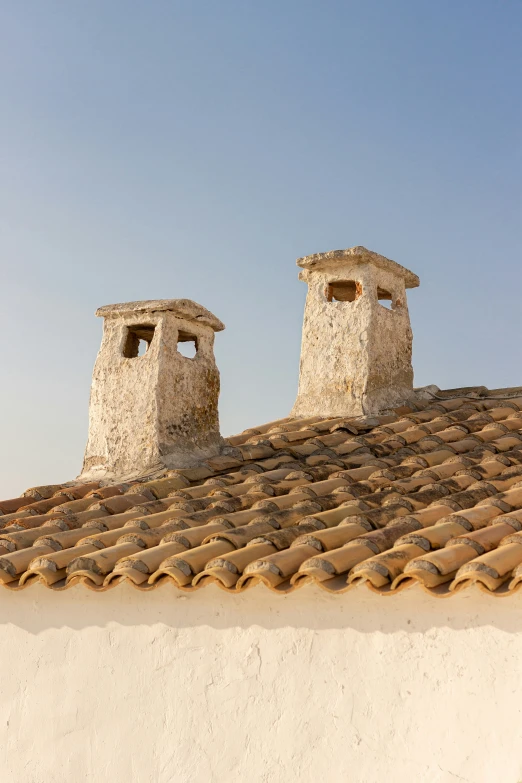 two stone chimneys on top of a white building