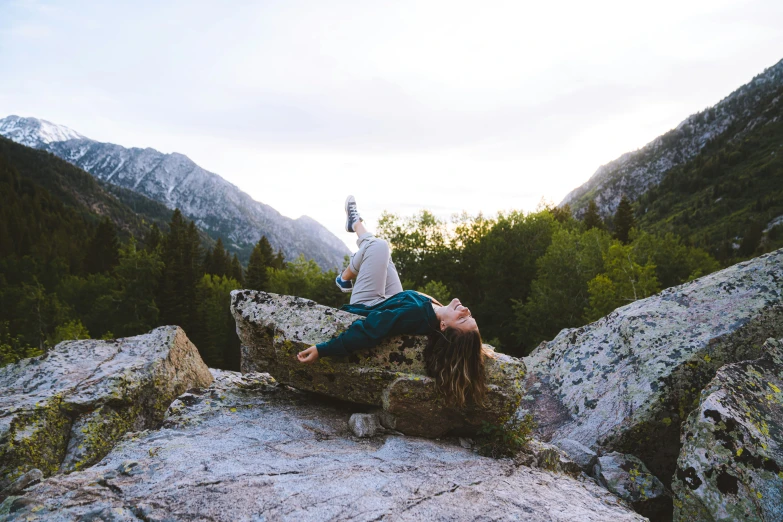 a woman laying on a rock while holding a cell phone to her ear