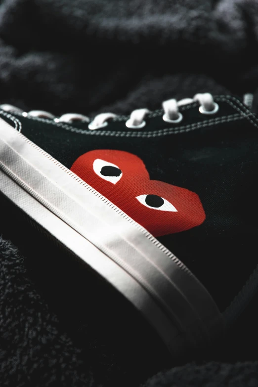 an odd red heart has been embroidered onto black sneakers