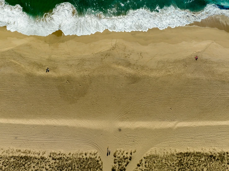 a couple walking on the beach towards the ocean