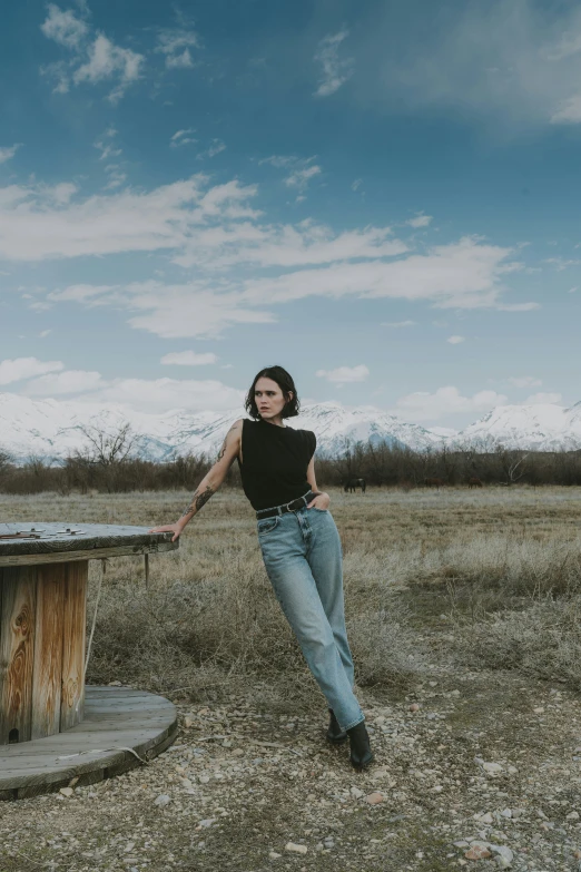 a woman is standing in a field by an old tree stump