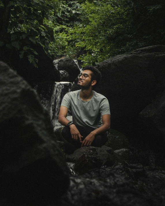 a man sitting on the ground next to water