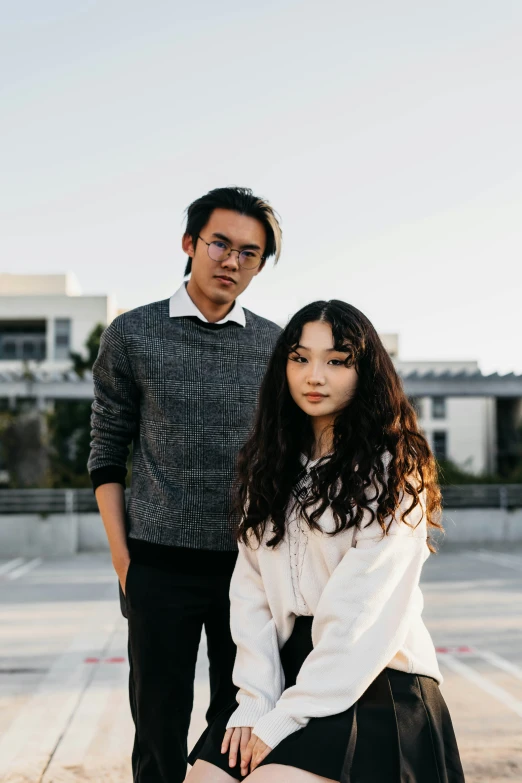 young woman with long hair and black skirt standing next to an asian man