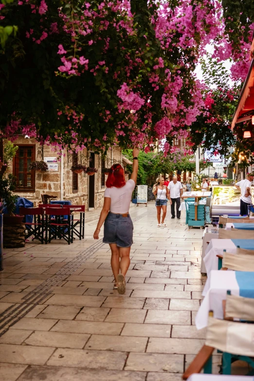 a women in grey shorts is holding onto purple flowers on her head