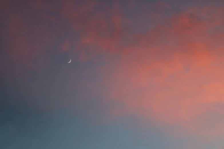 a moon and cloud in the sky as the sun sets