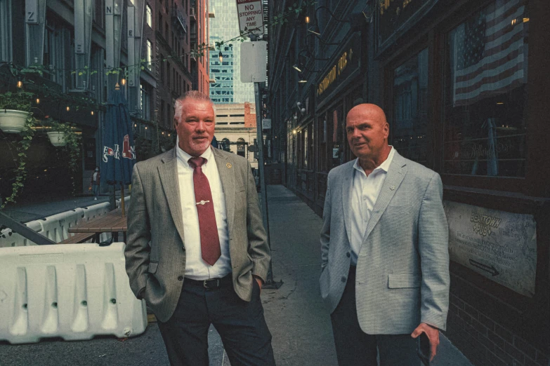 two men are standing on the street wearing jackets and ties