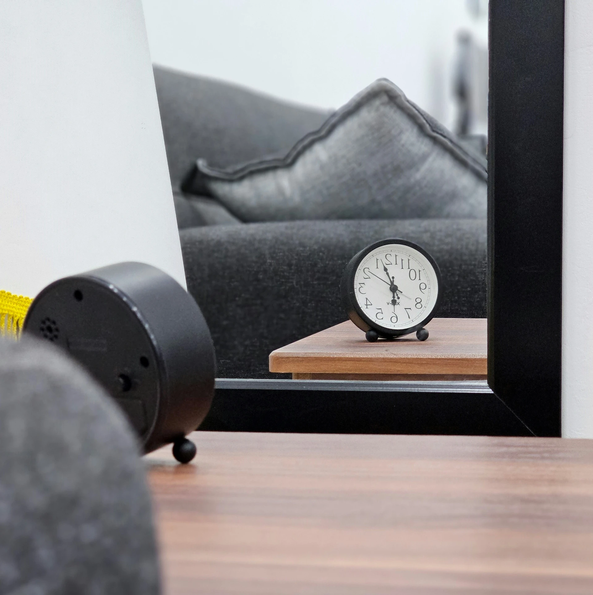 a small clock is sitting on a wooden surface near a sofa