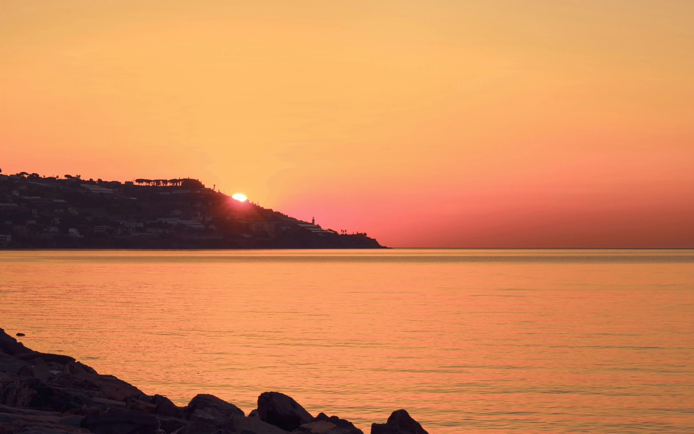 a large body of water with a lighthouse and mountains in the distance