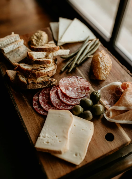 a large variety of meat and cheeses sitting on a wood table