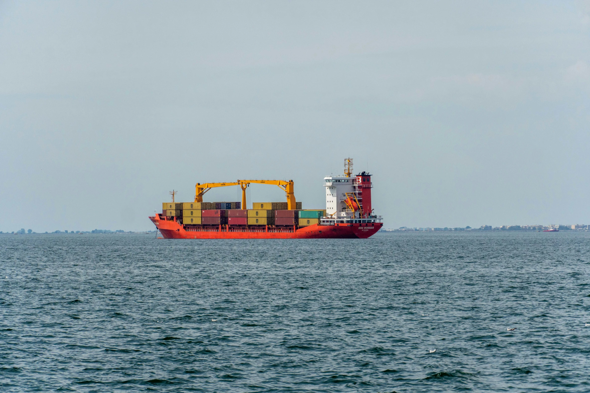 an orange and white cargo ship in the ocean