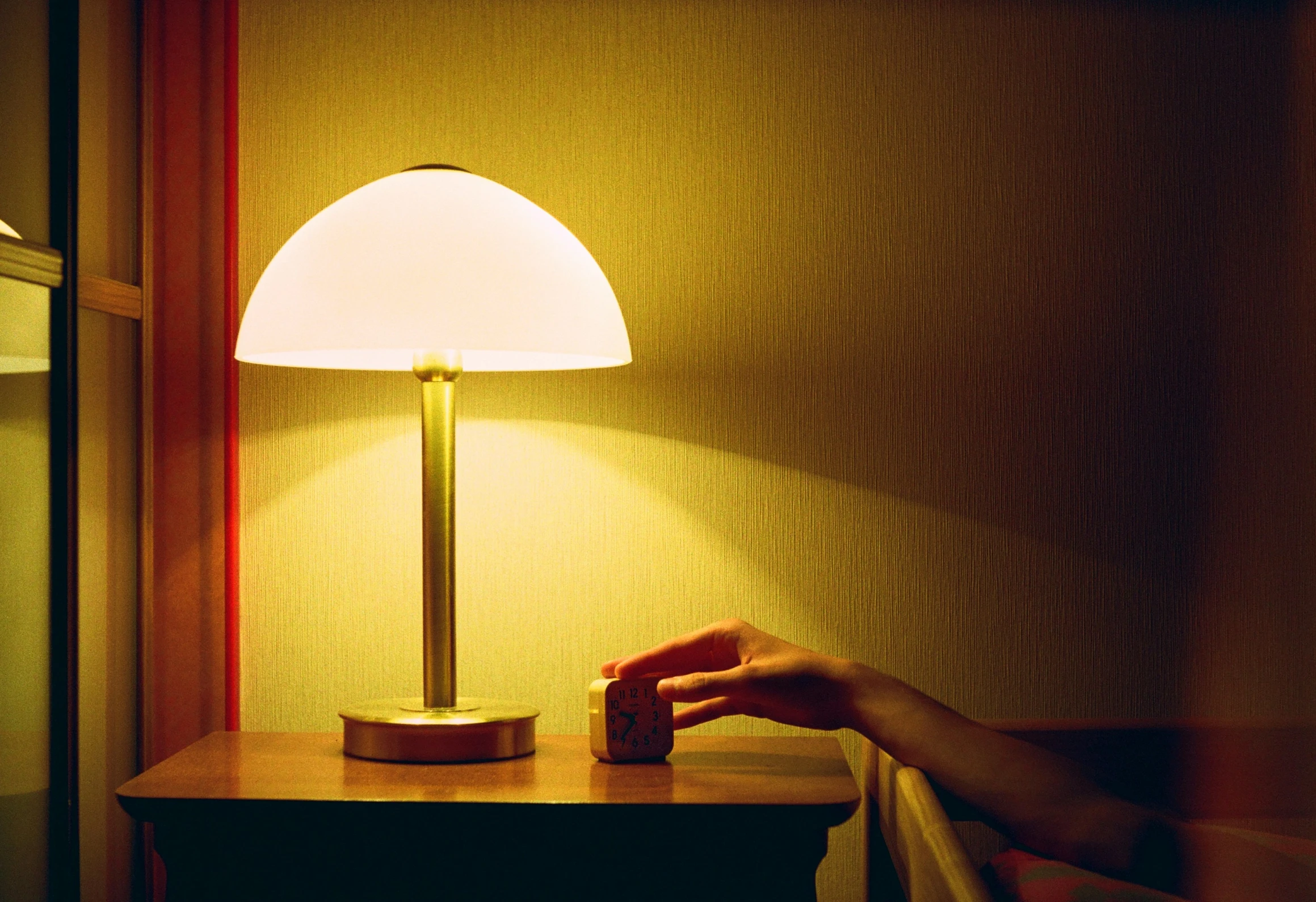 someone holding onto a lamp next to a wooden table