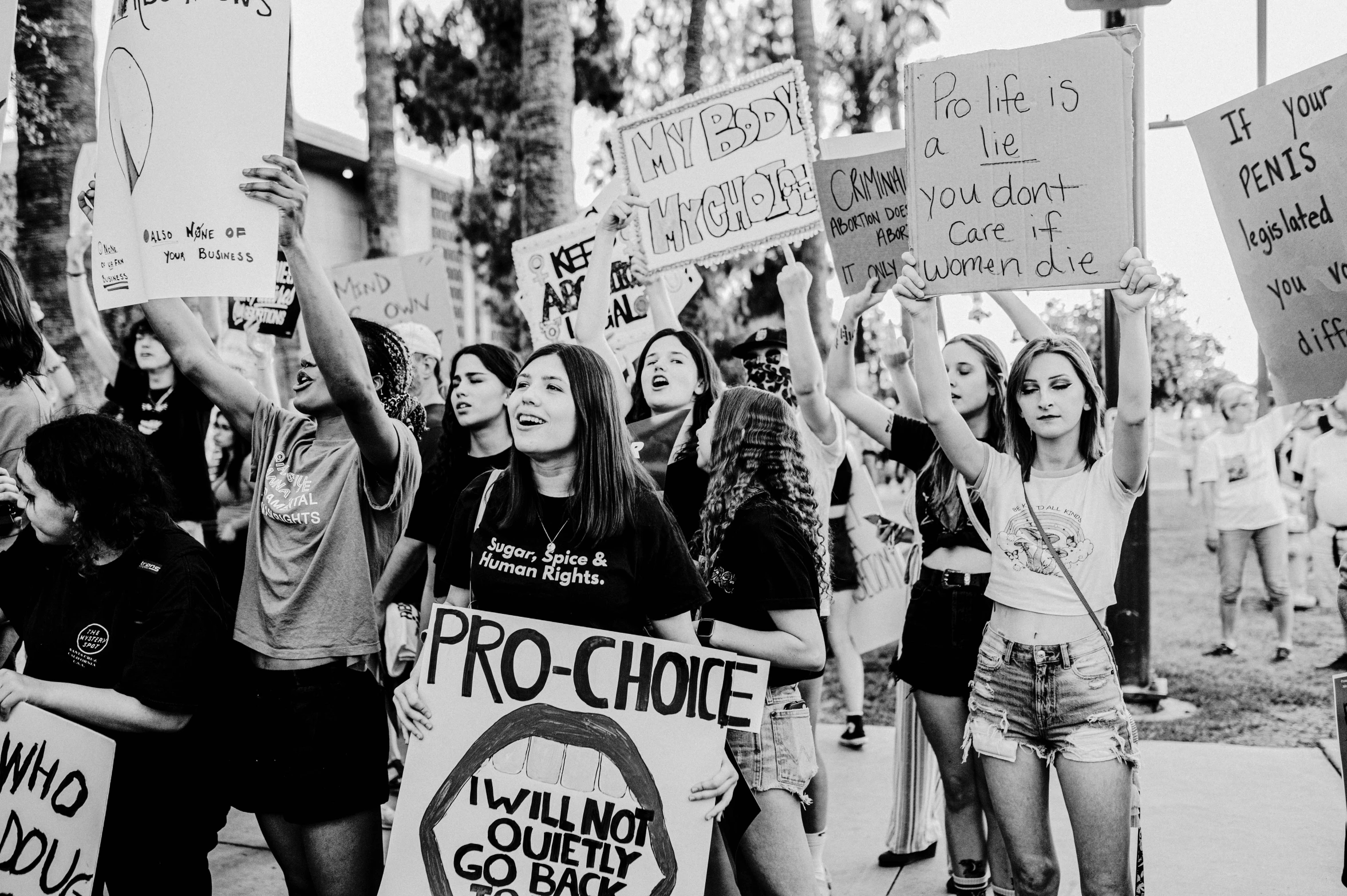 a group of girls with protest signs, holding up their hands