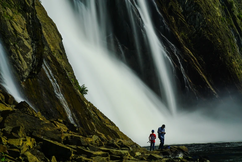two people stand at the base of an old waterfall