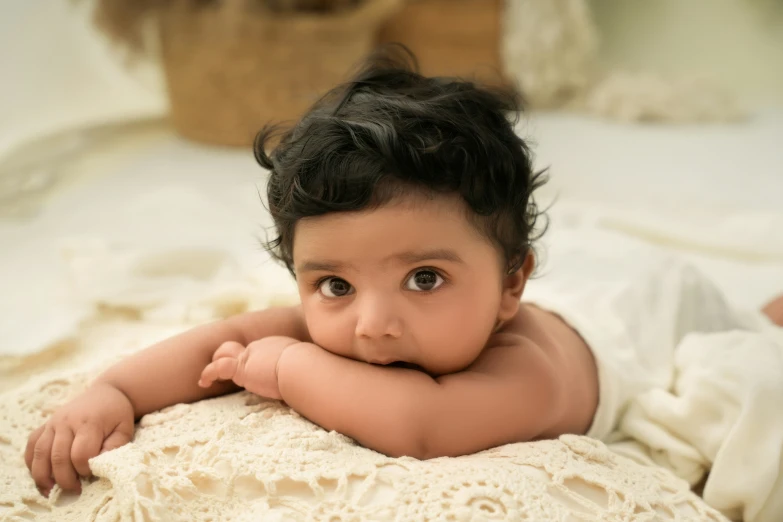 an infant girl looking straight ahead lying on her belly