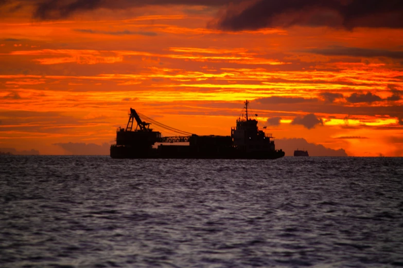 the boat is sitting in the calm ocean at dusk