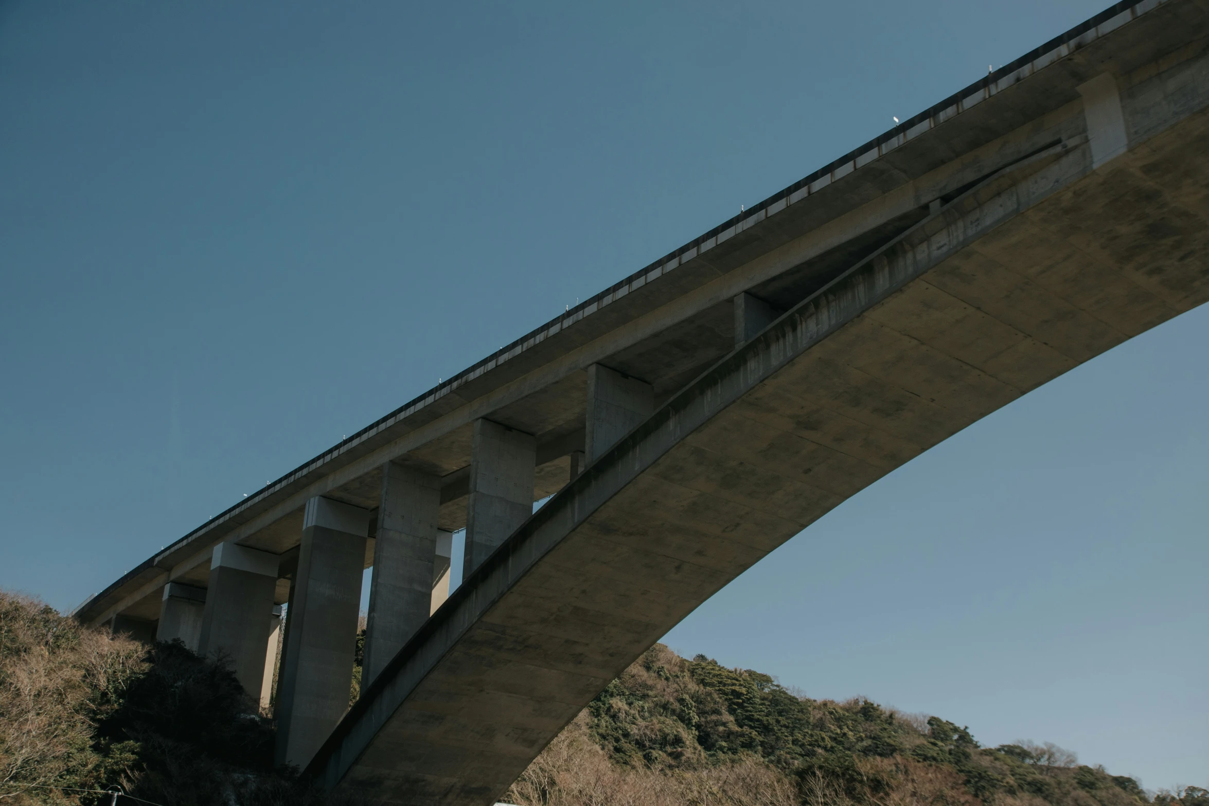 a tall bridge over a green hillside with a surfboard on it