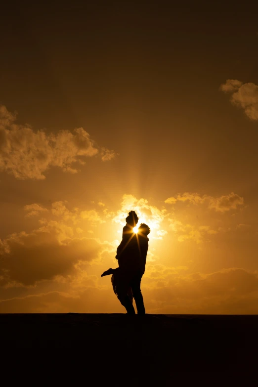 the silhouette of two people kissing against a sunset