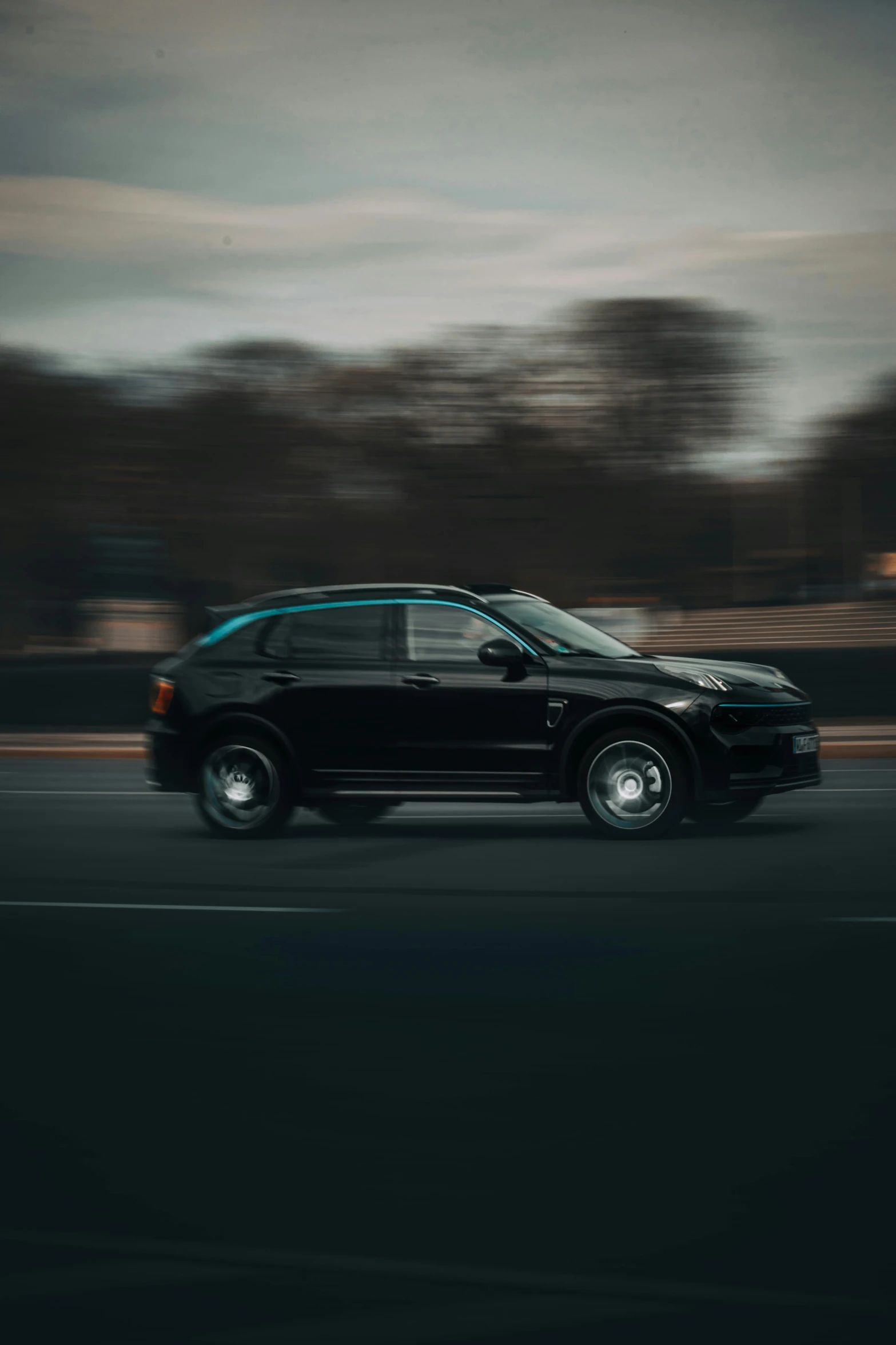 a black suv driving down the road on a cloudy night