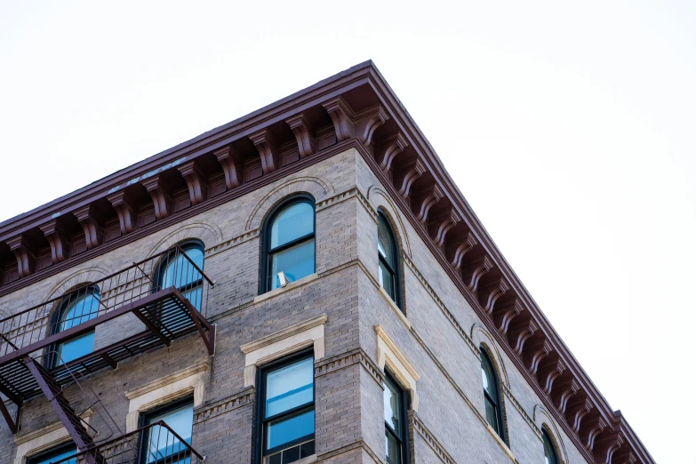 a tall brick building with multiple windows and a balcony